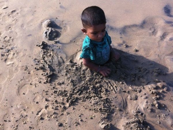 A young boy playing in the wet sand on a Sri Lankan beach