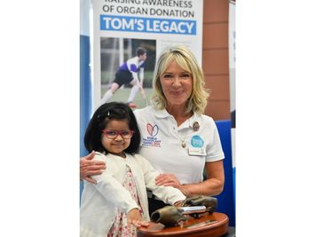 A volunteer and a young girl at the Tom's Legacy organ-donation awareness stand