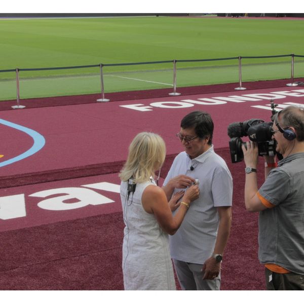 An organ-donation awareness interview being filmed pitchside at a football stadium